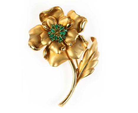 A gold emerald set flower design clip brooch, with satin finish leaf and petals, to a central cluster of navette shaped emera