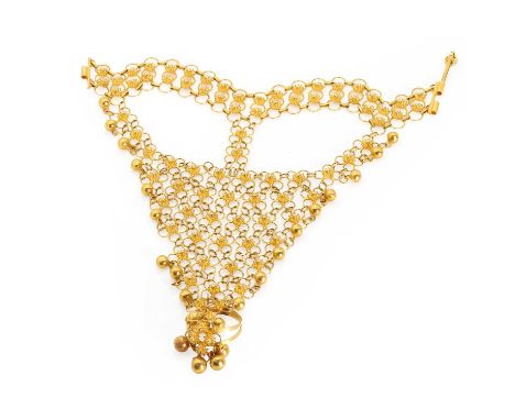 A Middle Eastern gold dorsal hand ornament, with floral motif links embellished with cannetille work and pendant gold beads. 