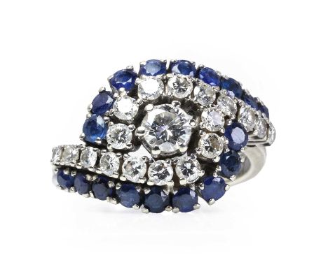 A white gold sapphire and diamond crossover ring,  with a principal round brilliant cut diamond, claw set, surrounded by a cr