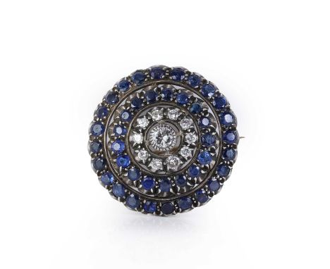 A diamond and sapphire target brooch/pendant,  an openwork boss with a round brilliant diamond rub set to the centre, encircl