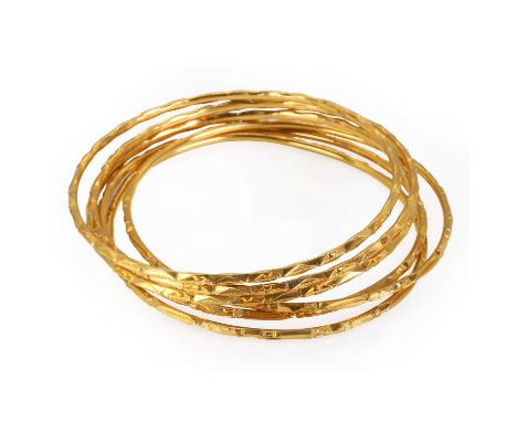 A group of six high carat gold bangles, of a similar design with textured and polished facets, all bearing foreign marks, tes