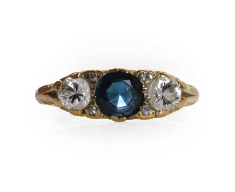 An 18ct gold sapphire and diamond three stone ring,  with a central round mixed cut sapphire, flanked with two round brillian