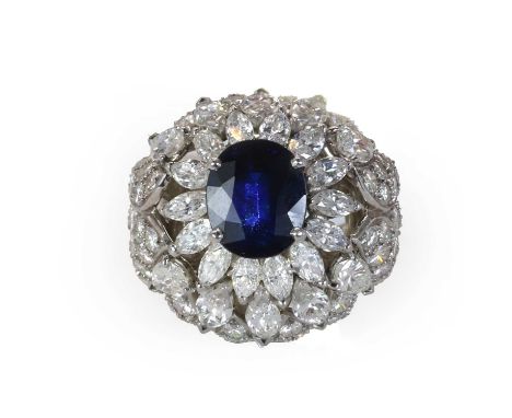 A mid 20th century sapphire and diamond bombé ring,   with an oval mixed cut sapphire claw set within two tiers of marquise a
