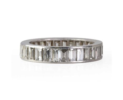 A diamond full eternity ring,  with a line of baguette cut diamonds channel set to a flat profile hoop, 4.50mm wide. Unmarked