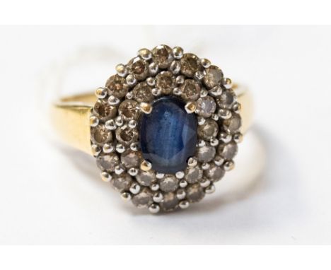 A sapphire and diamond cluster 18ct yellow gold ring,m the centre oval cut sapphire measuring approx 7 by 5 mm with diamond t