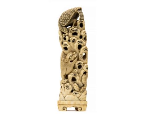 A late 19th Century Chinese ivory tusk carving of a beast, a serpent and an eagle on a rockface, integral scroll plinth, heig