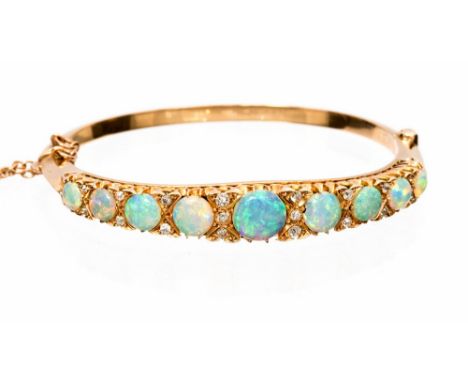An Edwardian opal and diamond set hinged yellow gold bangle, nine graduating round cabochon cut opals graduating between 8.5m