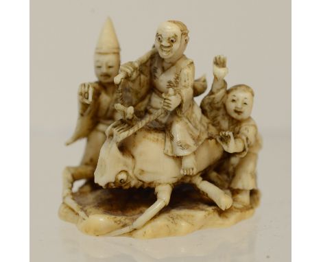 A Japanese ivory netsuke of a figure rising a beetle flanked by two other figures, Meiji period, 1868-1912, width 3cmPedigree