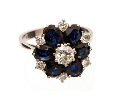 A diamond and sapphire flower head cluster 18ct white gold ring, central round brilliant cut diamond and six smaller brillian