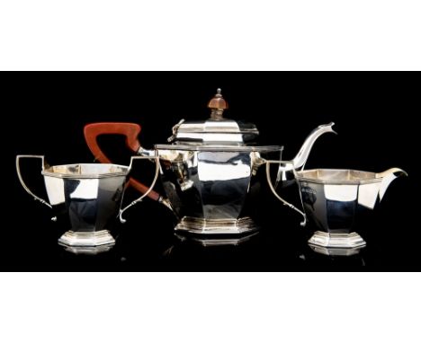 A George V silver three piece tea service, plain octagonal section with reeded borders, the teapot with hardwood c-scroll han