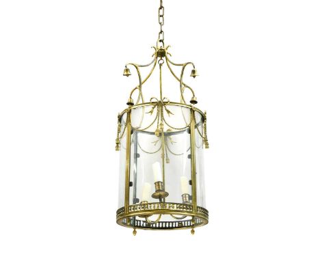An Edwardian brass hall lantern, of cylindrical form with three branch candle holder, with brass bows and swags suspended fro