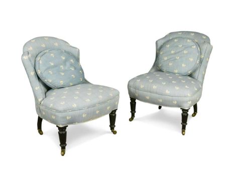 A pair of ebonised nursing chairs, early 20th century, upholstered in a blue fabric with floral motif, on turned front legs a