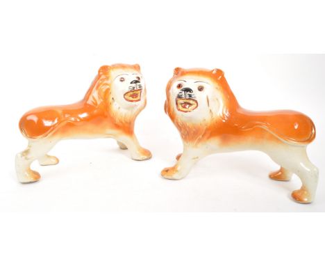 A pair of 19th century ceramic pottery fireside Staffordshire wild cat lions. In standing positions in orange and white groun
