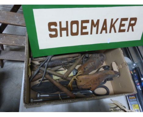A collection of shoemaking tools, along with a vintage shoemaker sign
