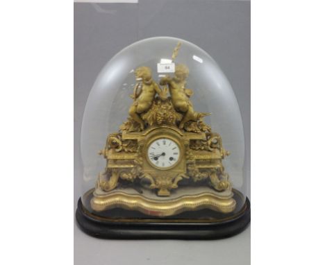 A 19th century gilt mantle clock, with a white enamel dial, on a shaped wooden base, in a glass dome