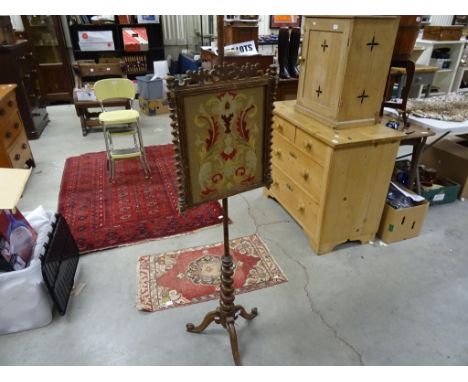 A Victorian oak pole screen, with a needlework tapestry, on a tripod base 