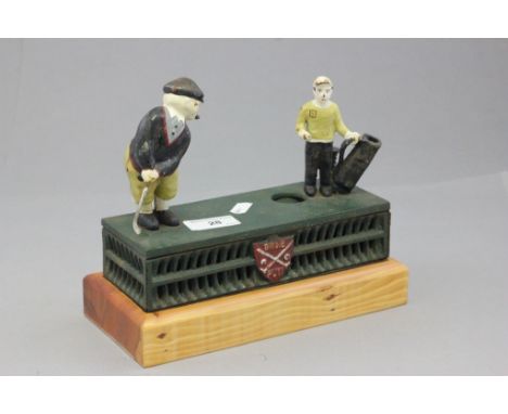 A vintage cast iron money box, of a golfer and caddy on a later pine base