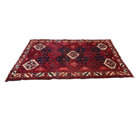 A Kurdish rug, 20th century, the red and navy field with repeating lozenges within a geometric border,286 x 137cmCondition Re