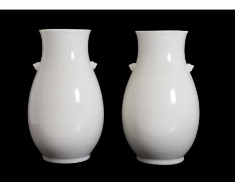 A pair of Japanese white-glazed vases,  of ovoid form flanked by Buddhist lion handles, decorated with a band of key fret to 