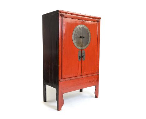 A red lacquered wedding cabinet, 20th century, Chinese, the twin doors with brass fittings, enclosing shelves and internal dr