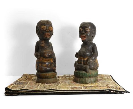 A pair of carved hardwood tribal figures,  20th century, painted in polychrome, 48cm and 46cm high together with an embroider