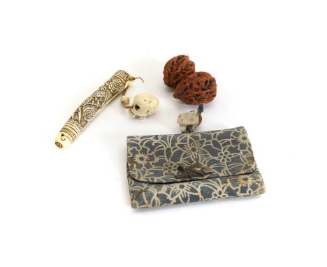 A pair of Chinese carved nuts,  decorated with men among blossoms, 5cm and 4.5cm long, together with a small purse with a flo