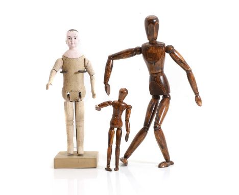 A carved wooden doll,  late 19th century, with articulated legs and arms and a painted head, with stand, 31cm high 33.5cm ove