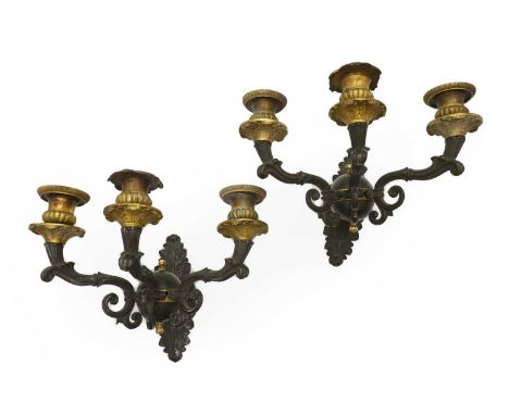 A pair of Regency patinated and gilt bronze three branch wall appliques, early 19th century, the foliate cast bosses, each is