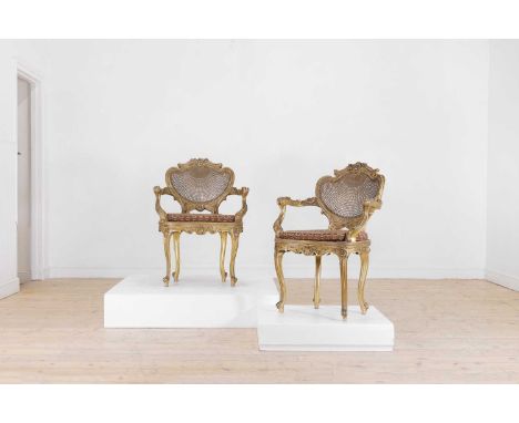 A pair of Louis XV-style giltwood salon chairs, late 19th century, French, each with a caned back and seat, with all-over scr