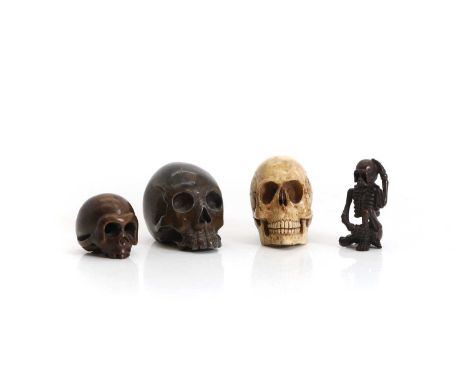 A collection of skulls,  including a stylised bronze skull, with markers marked to the base, 5cm high, a realistic bone examp