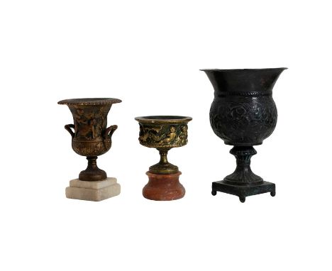 A gilt metal campana form urn, 20th century, having twin handles wth relief figural decoration on a white marble plinth,22cm 