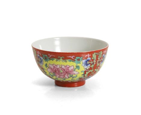 A Chinese famille rose bowl, of circular form, painted with peony enclosed by blossoming floral borders, all against a coral 