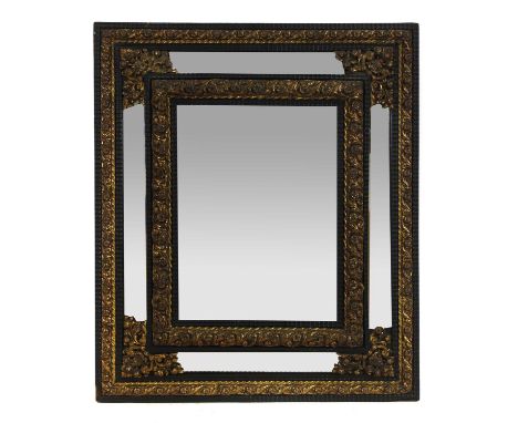 A Northern European brass and ebonised cushion mirror,  19th century, the central bevelled plate within a press moulded frame