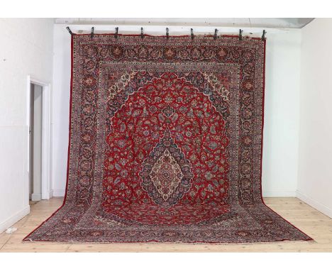 A Kashan carpet, mid-20th century, with a central floral medallion to a red field, and a triple navy and red border,440 x 310