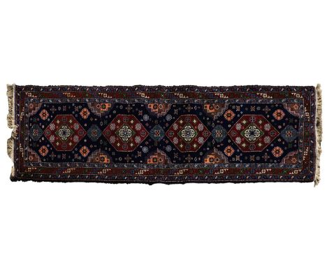 A Persian style runner, 20th century, with repeating central medallions to a dark navy field, within a triple border,296 x 85