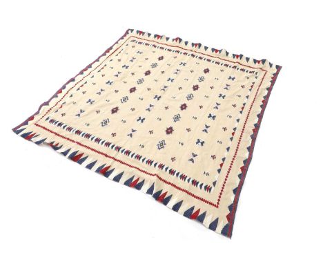 An embroidered table cloth or bed cover, 20th century, with geometric spot motifs in predominantly red and blue threads, on a