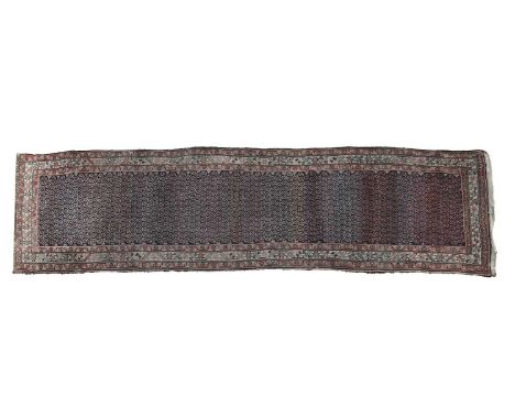 A Persian Beluchi runner, 20th century, the dark field with repeating leaf motifs, with red and buff borders,110 x 265cmCondi