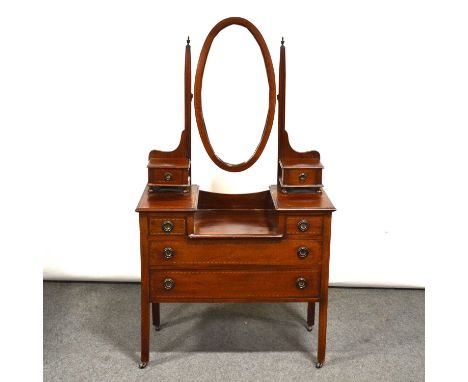 Edwardian mahogany dressing table, oval mirror above trinket drawers, the base with further drawers, square legs on casters, 