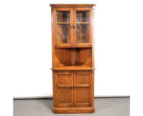 Ercol elm freestanding corner cabinet, the upper section with glazed doors, the base with open shelf and a cupboard, height 1