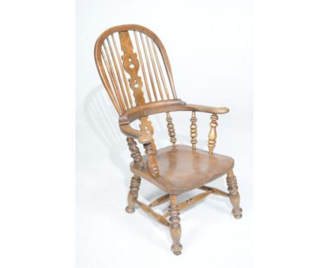 A Victorian beechwood and elm comb highback elbow chair
With a pierced splat, outswept arms supported by turned spindles, dis