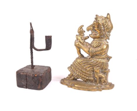 An antique rush light holder
With a spirally twisted support raised upon a square wooden base, 23cms high and a brass doorsto