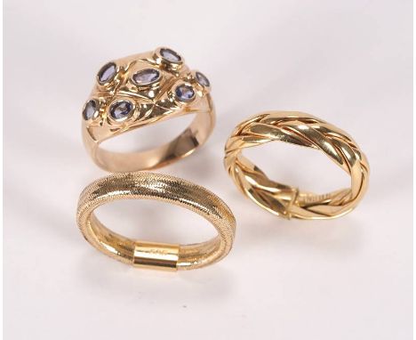Drei GoldringeGelbgold 585. Ein Ring mit geflochtenem Band, einer mit  flexiblem Band und ein Ring breitem Ringkopf und Glass