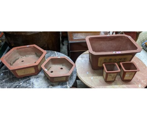 A group of oriental terracotta Bonzai style garden planters, each with cream panels of floral decoration and calligraphy line