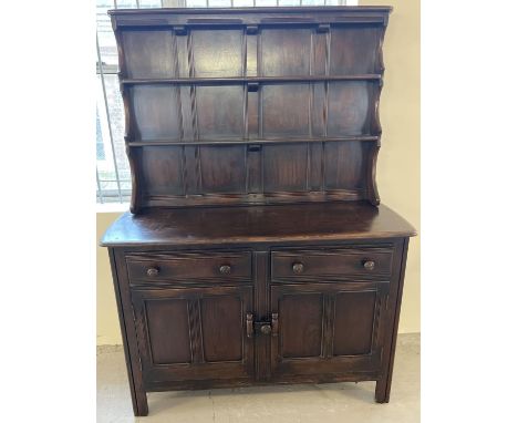 A vintage Ercol small double dresser in dark wood. Two shelves to top with shaped sides. 2 door and 2 drawer base with cutler