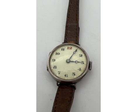 An antique silver cased Swiss 15 jewels wristwatch with brown leather strap. White enamel face with black and red hour marker