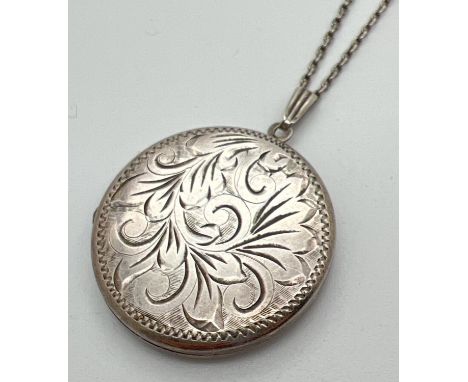 A vintage silver locket with foliate design engraving to front, on a 24" white metal chain. Locket approx. 3.25cm diameter. T