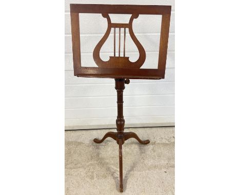 A vintage wooden music stand with tripod feet, turned pedestal shaft and lyre design to tray. Wooden pegs for adjusting angle