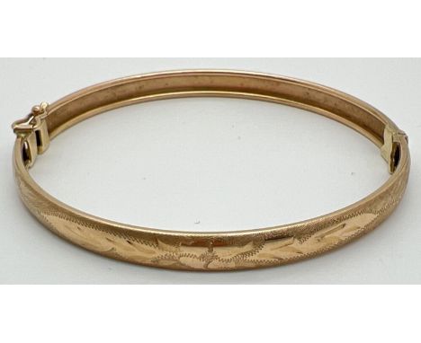 A vintage 9ct gold bangle with half floral engraving and safety clip (in need of attention) to clasp. Hallmarks to push clasp
