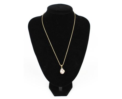 A modern 9ct gold fancy rope link necklace hung with a gold-plated, paste and cream enamel egg-shaped pendant. The necklace o