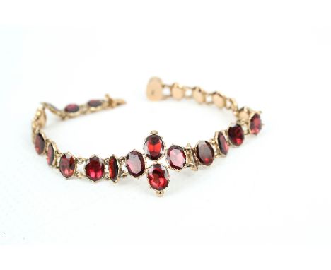 A Victorian rose gold and garnet bracelet in the 18th century style. Designed as a row of 21 oval foil-backed garnet closed-b